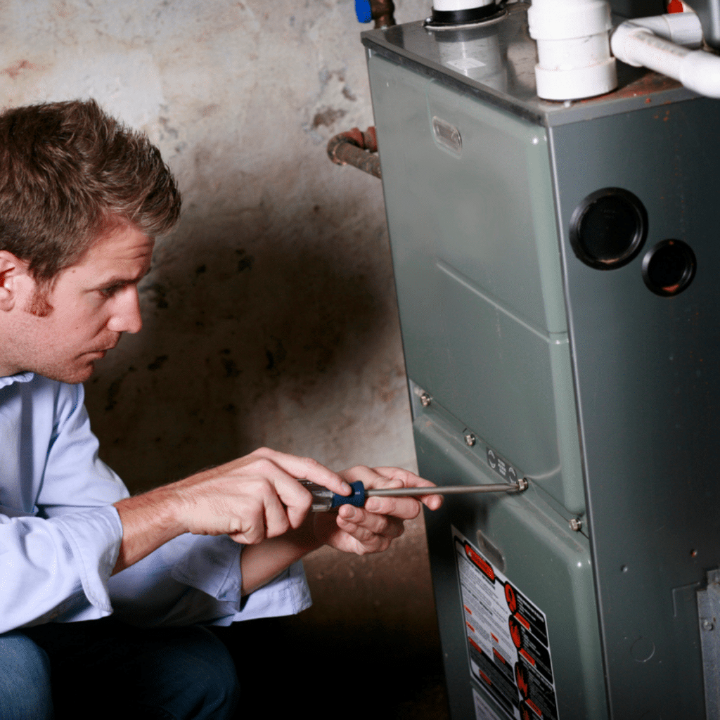 Technician using a screwdriver to work on a furnace system