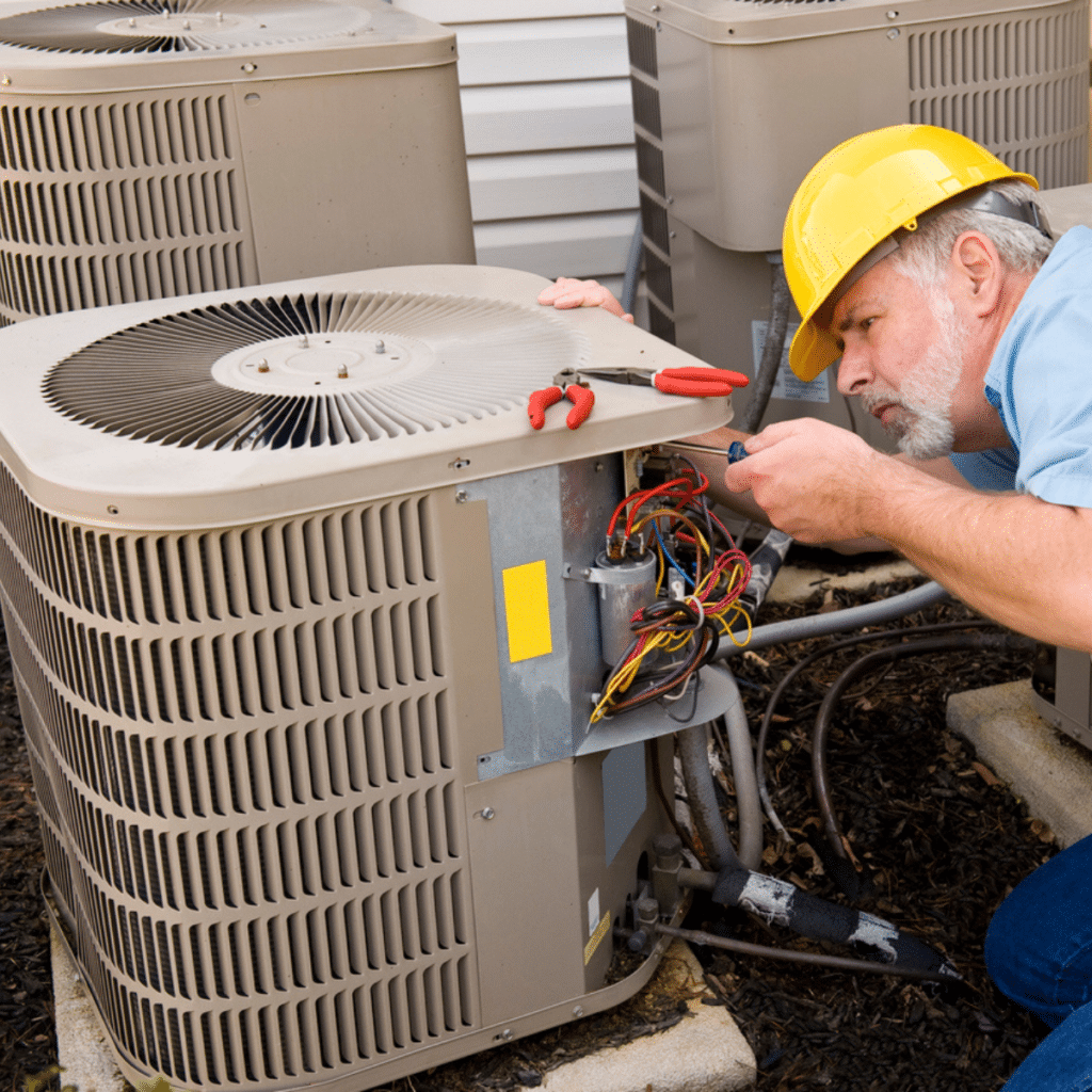 Technician repairing an outdoor AC unit with tools and wires exposed