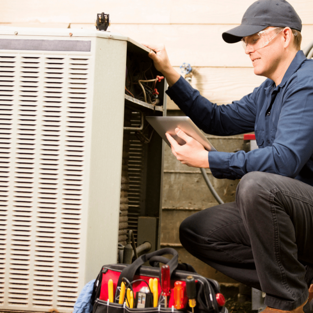 Technician inspecting an HVAC unit with a tablet and tools nearby