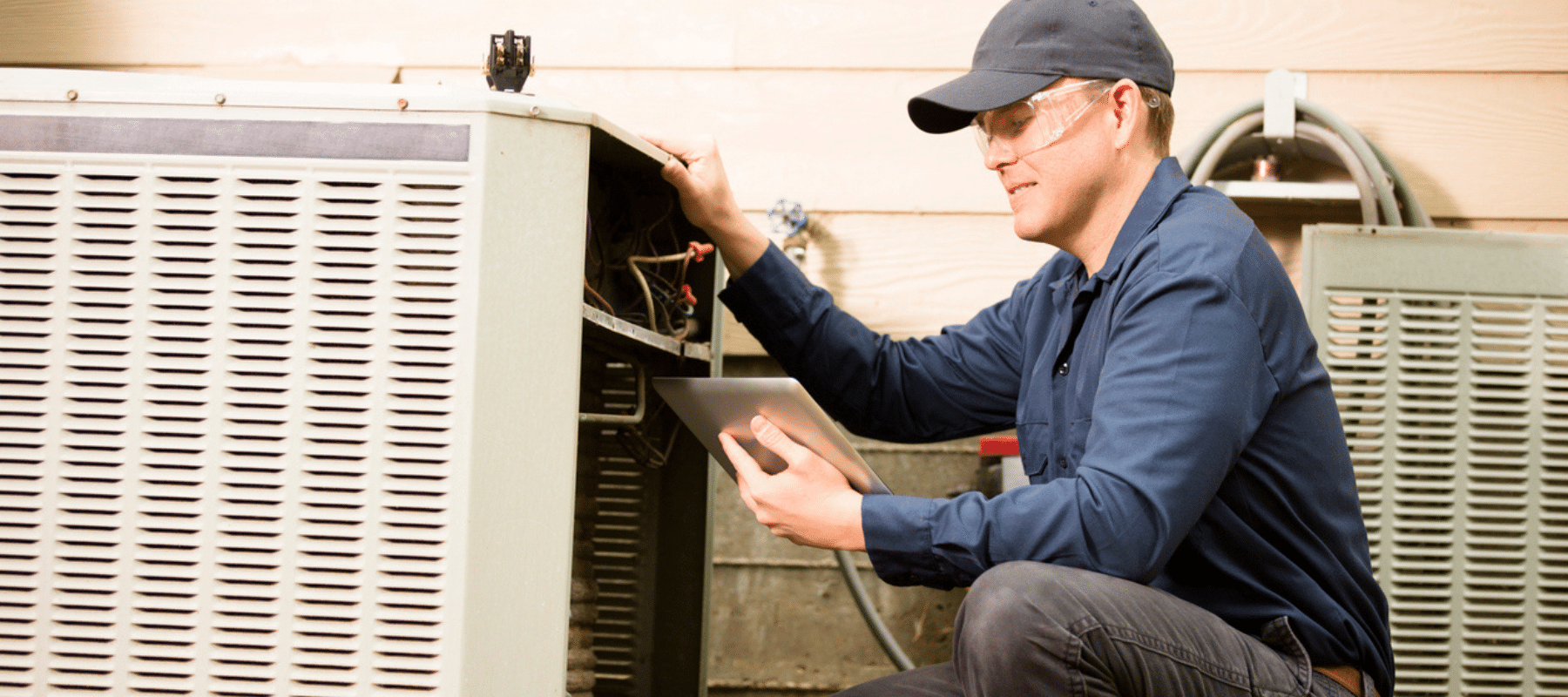 Technician inspecting an HVAC unit with a tablet and tools nearby