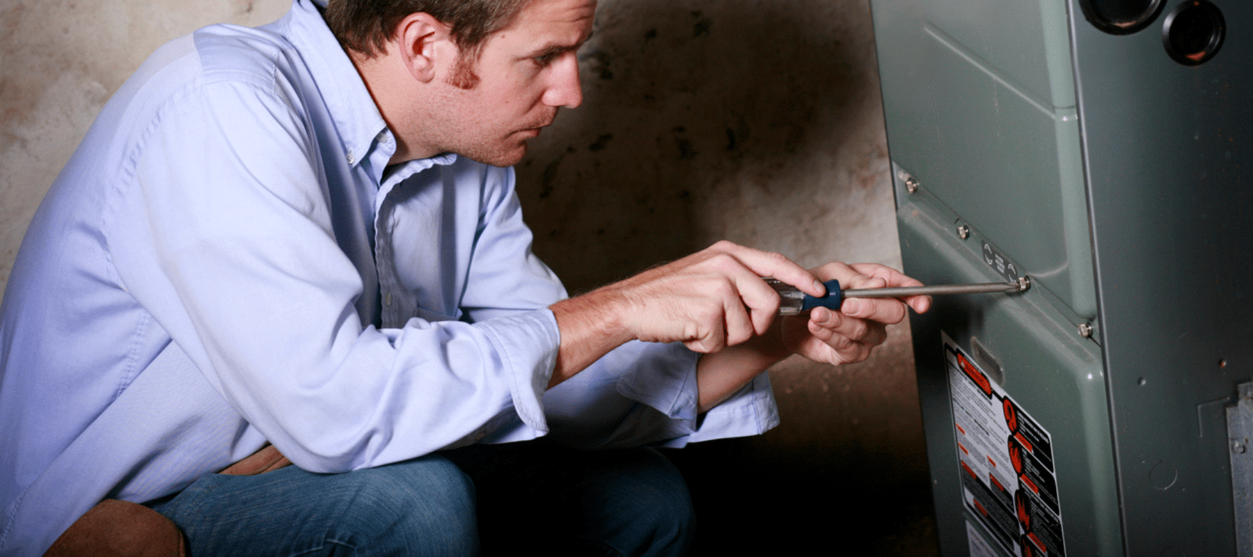 Technician using a screwdriver to work on a furnace system