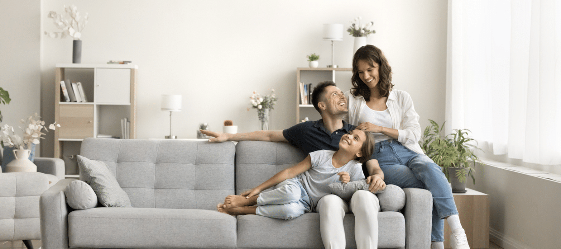 A family of three sitting on a gray couch, enjoying a comfortable and cozy living room atmosphere