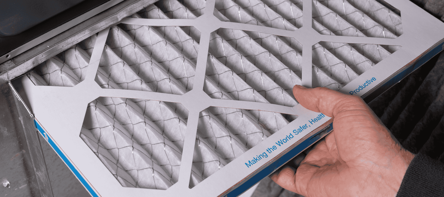 A close-up of a hand replacing an air filter in an HVAC system, emphasizing clean and efficient operation