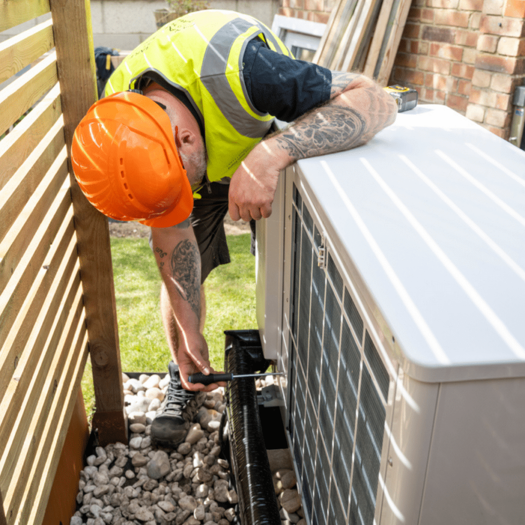 A technician in safety gear servicing an outdoor HVAC unit, showcasing professional maintenance