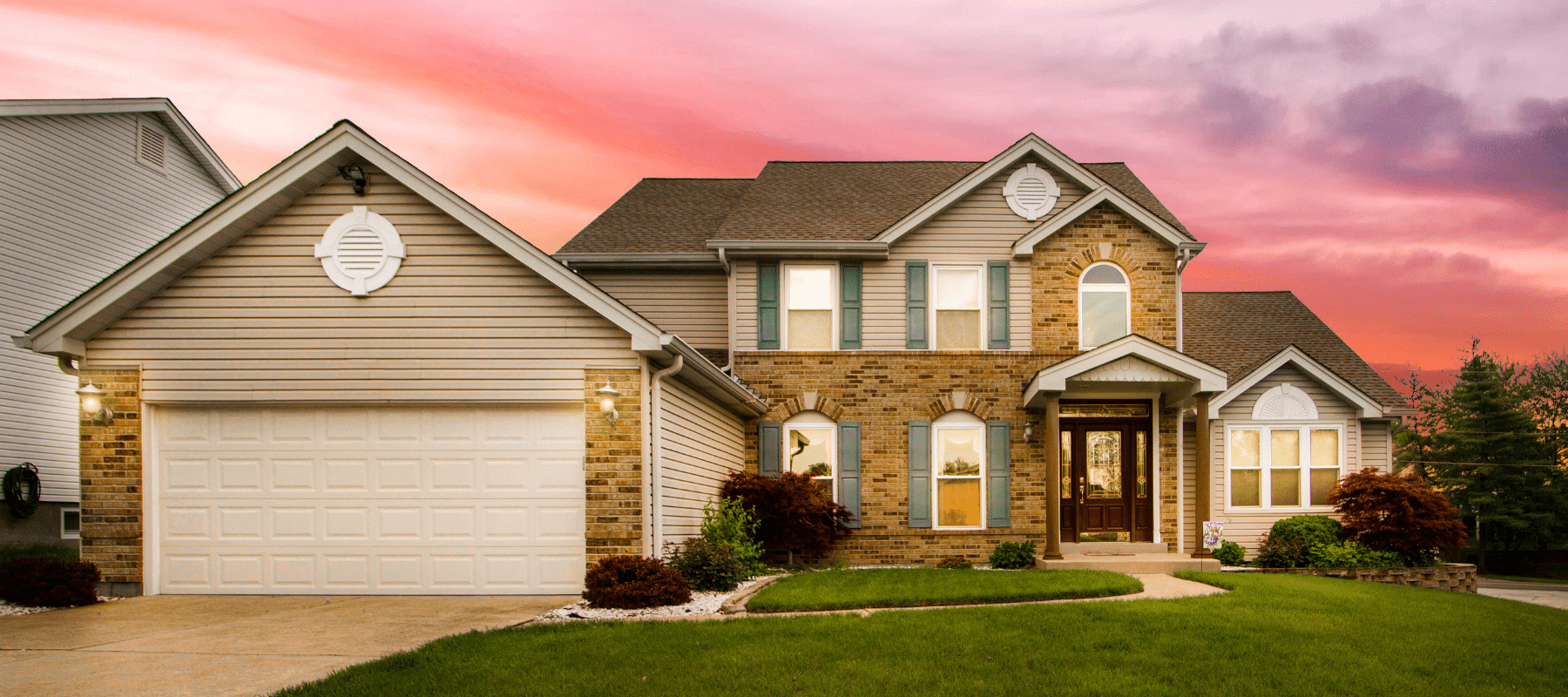 residential home with kept green yard during a pink and purple sunset